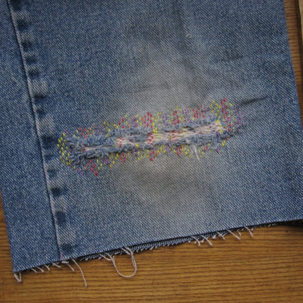 a colorfully darned denim tear