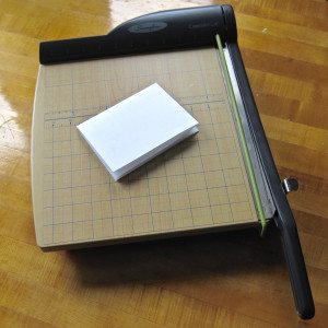 photo of paper folded in quarters lying on guillotine-style paper trimmer