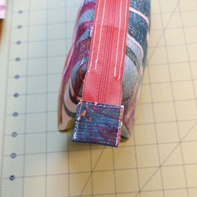 Bottom end of zipper enclosed in fabric tab